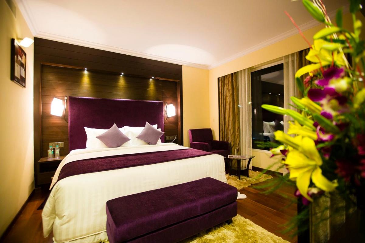 a bedroom with a large bed with a purple headboard at Sterlings Mac Hotel in Bengaluru