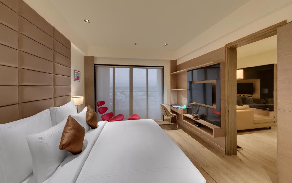 a hotel room with a large bed and a television at Wyndham Ahmedabad Shela in Ahmedabad