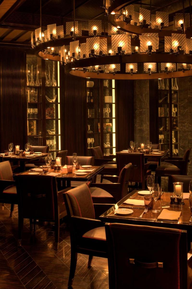 a restaurant with tables and chairs and a chandelier at Park Hyatt Hotel and Residences, Hyderabad in Hyderabad
