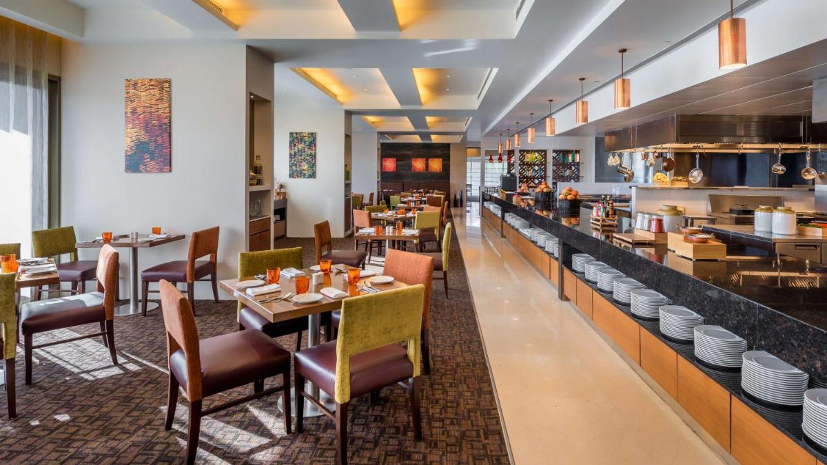 a restaurant with tables and chairs and a counter at Hyatt Place Pune Hinjawadi in Pune