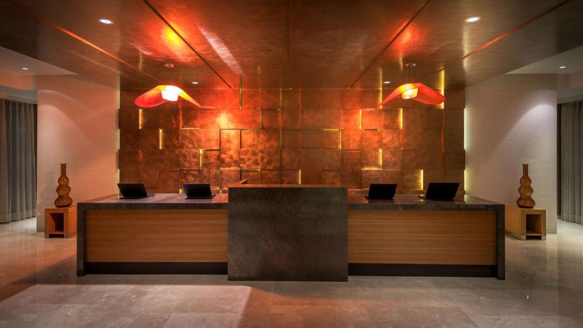 a lobby with a reception desk with two lights at Hyatt Place Pune Hinjawadi in Pune