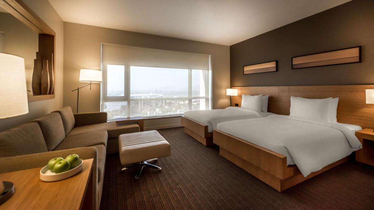 a hotel room with two beds and a couch at Hyatt Place Pune Hinjawadi in Pune
