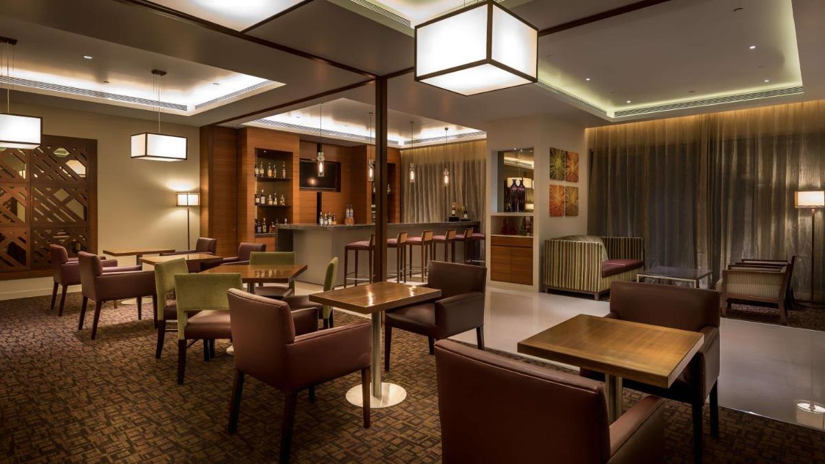 a restaurant with tables and chairs and a bar at Hyatt Place Pune Hinjawadi in Pune