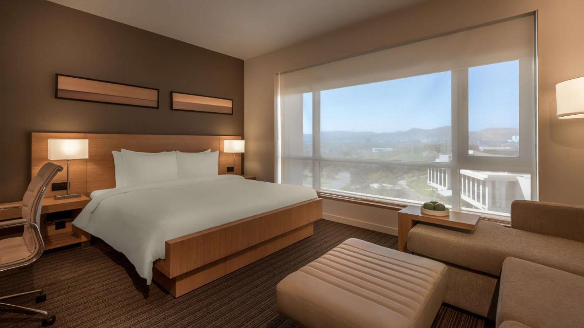 a bedroom with a bed and a large window at Hyatt Place Pune Hinjawadi in Pune