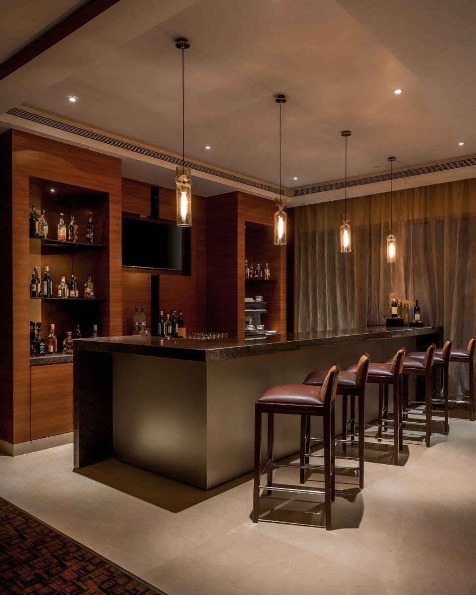 a bar with brown stools in a room at Hyatt Place Pune Hinjawadi in Pune