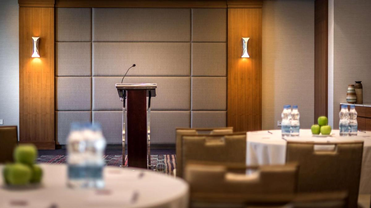 a podium in a room with tables and chairs at Hyatt Place Pune Hinjawadi in Pune