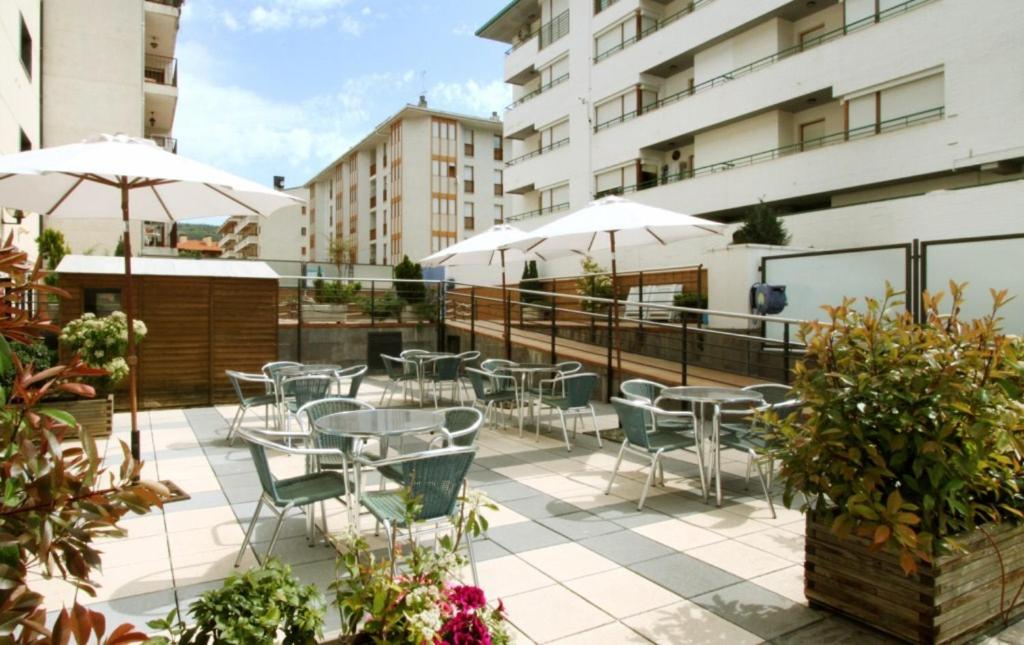 Un patio al aire libre con mesas, sillas y sombrillas. en Hotel & Spa Real Jaca, en Jaca