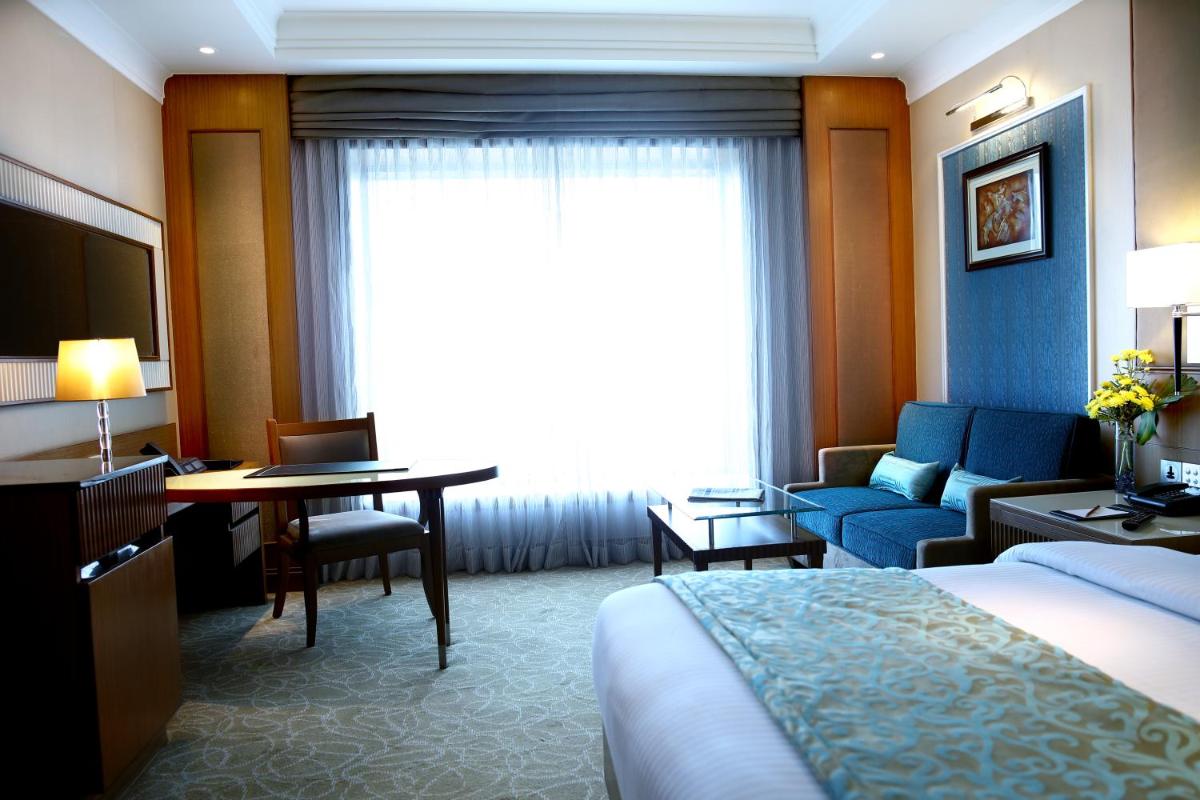 a hotel room with a bed and a desk and a couch at Ramada Plaza Chennai in Chennai