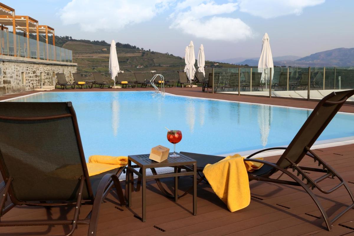 uma mesa e cadeiras ao lado de uma piscina em Douro Scala em Mesão Frio