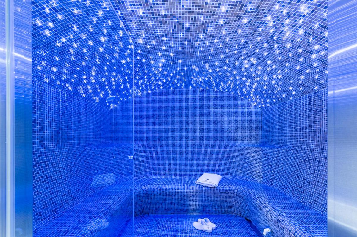 La salle de bains est pourvue de carrelage bleu, d'une douche et de toilettes. dans l'établissement Snow Lodge Hotel Courchevel 1850, à Courchevel