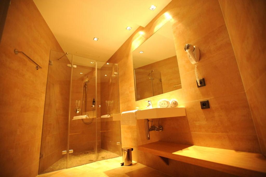 une salle de bain avec une douche, un lavabo et un miroir dans l'établissement La Source Des Sens, à Morsbronn-les-Bains