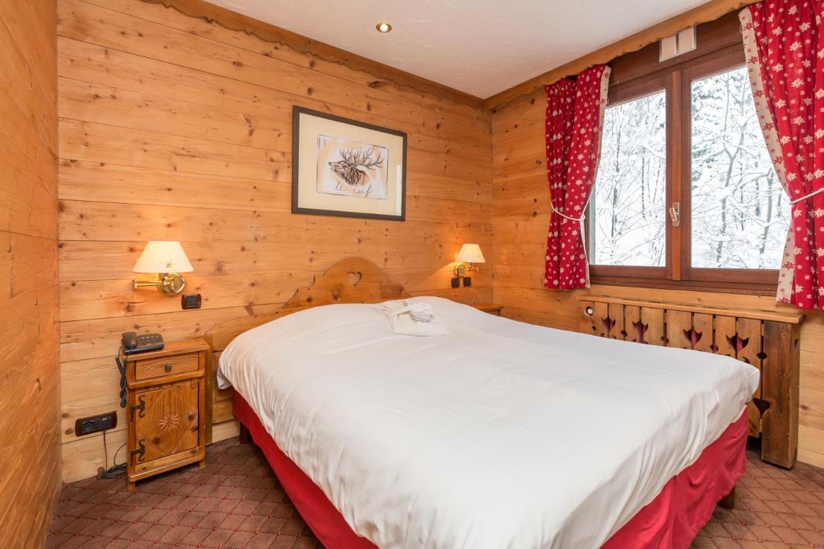 une chambre avec un lit dans une cabane en rondins dans l'établissement Carlina, à La Clusaz 32 autres photos