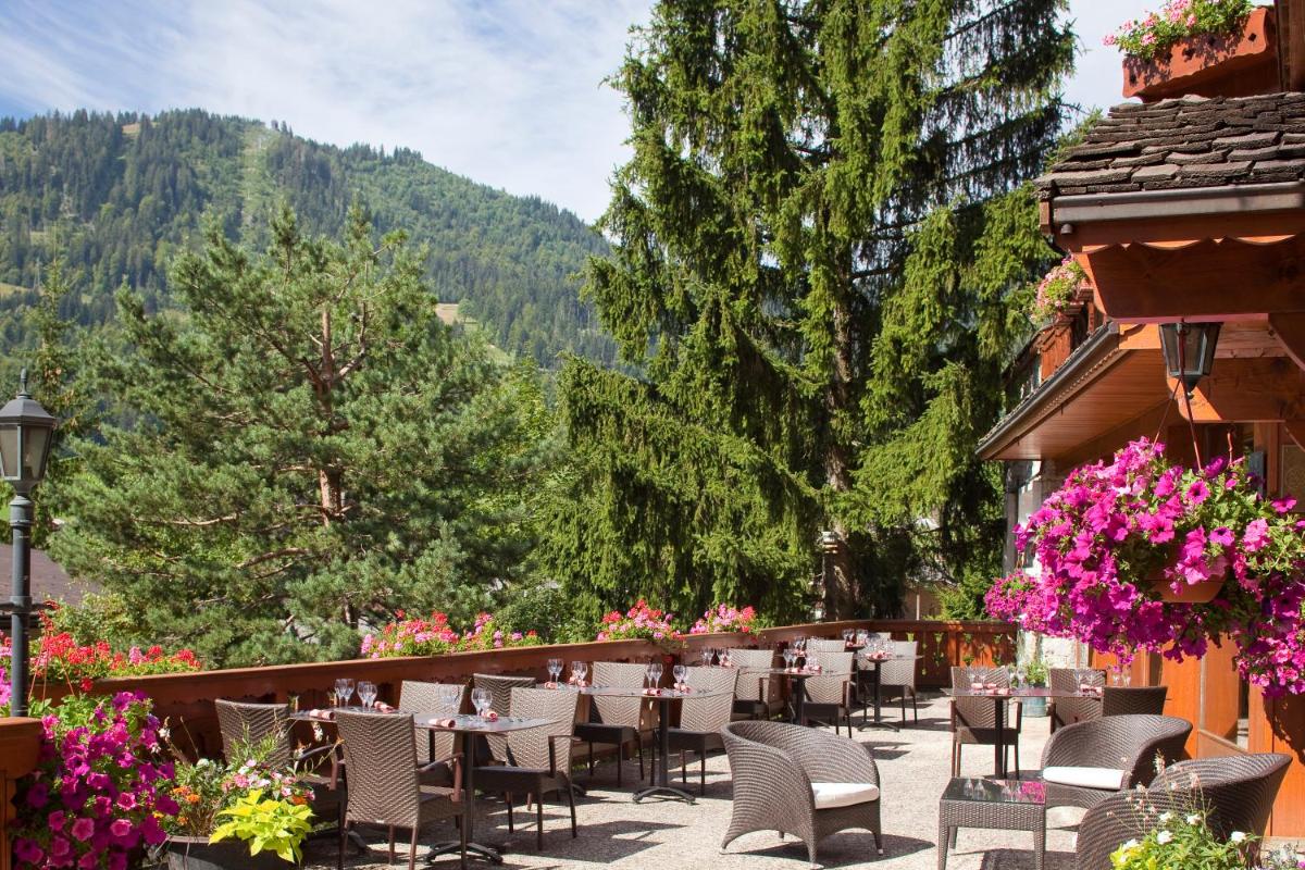 un restaurant avec des tables et des chaises sur un balcon dans l'établissement Carlina, à La Clusaz