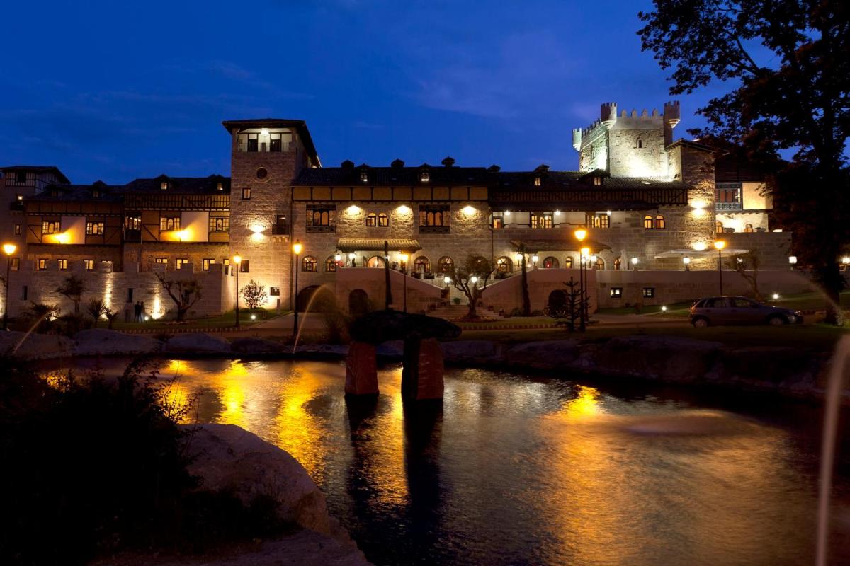 Un gran edificio de noche con un río al frente. en Hotel Termal Abadia de Los Templarios, en La Alberca