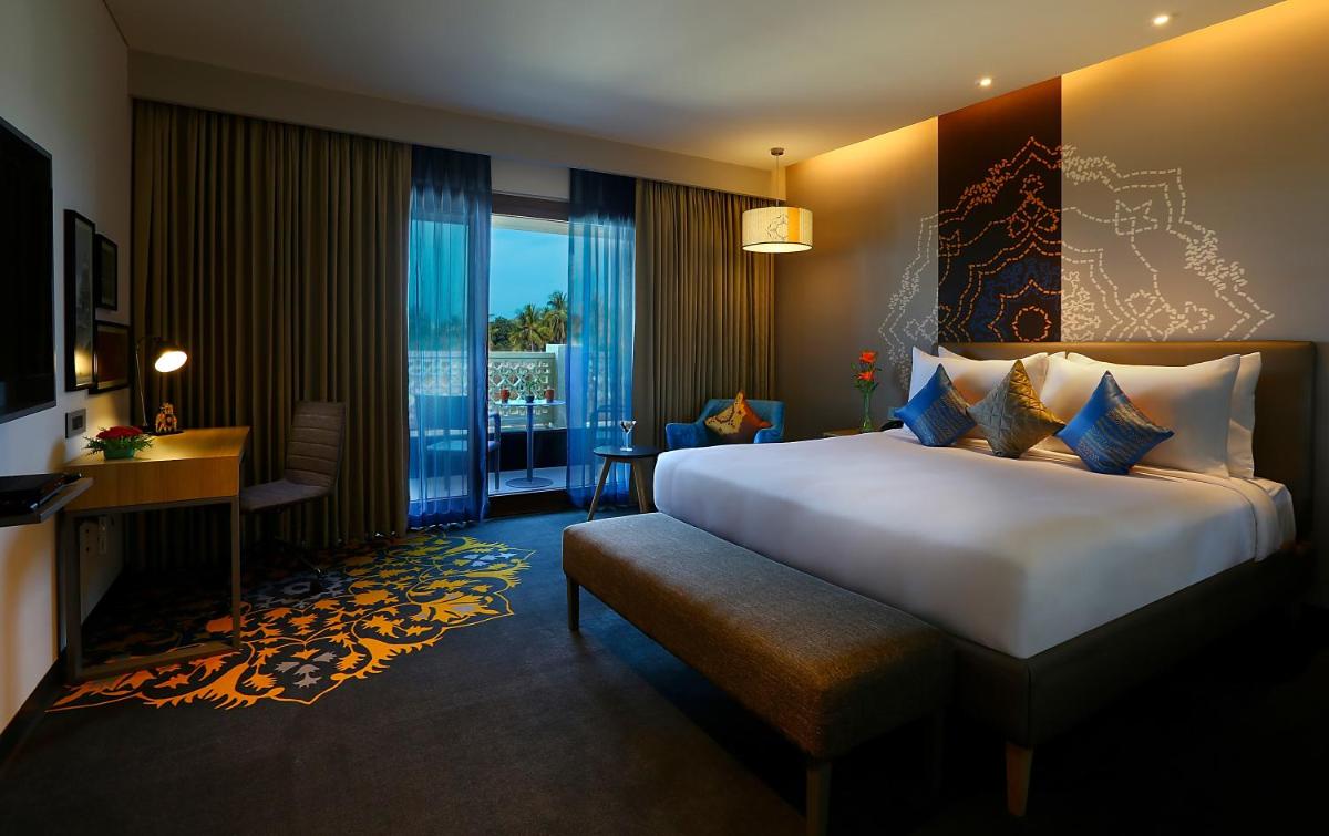 a hotel room with a large bed and a desk at Grand Mercure Mysore - An Accor Brand in Mysore