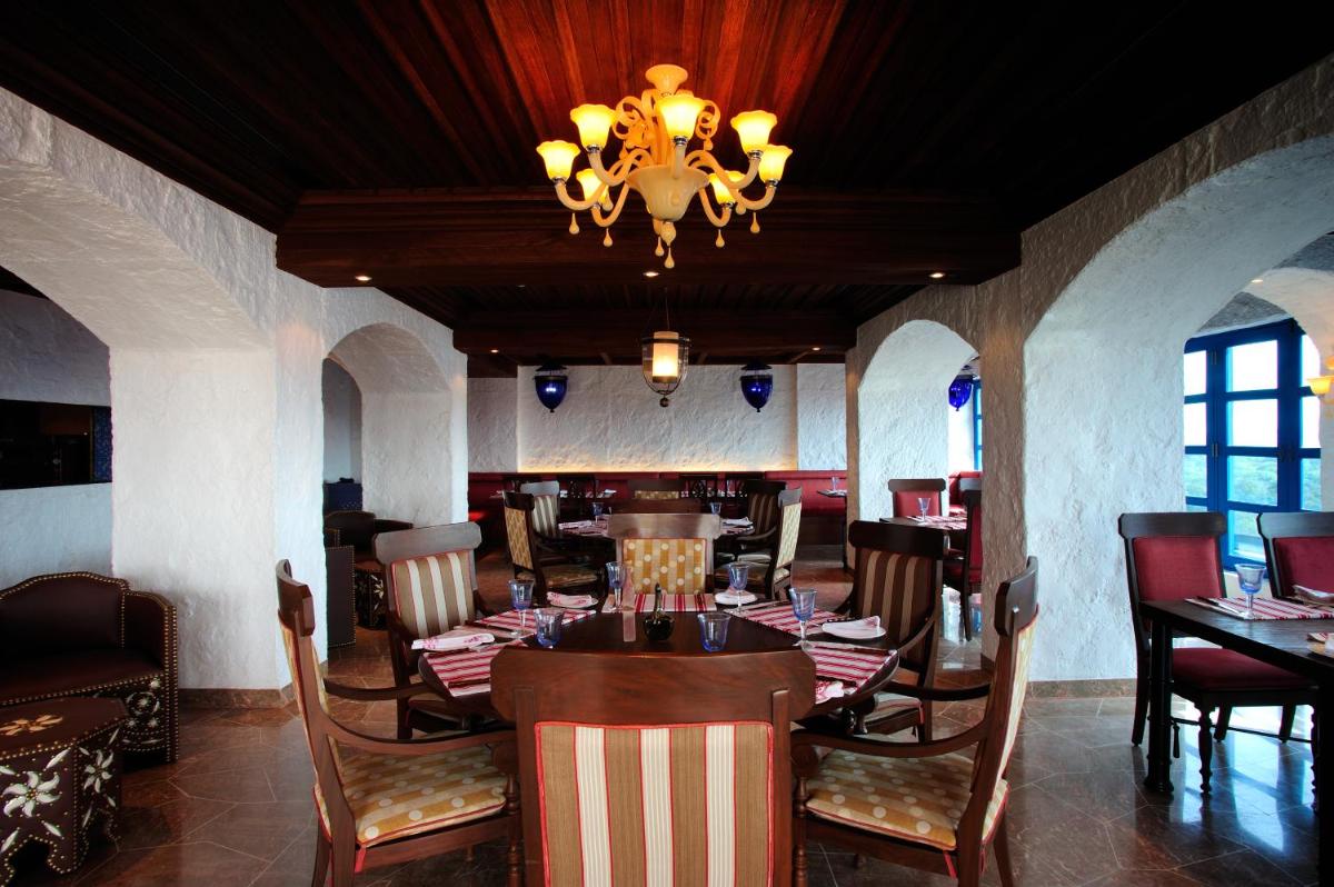a dining room with a table and chairs and a chandelier at Taj Club House in Chennai