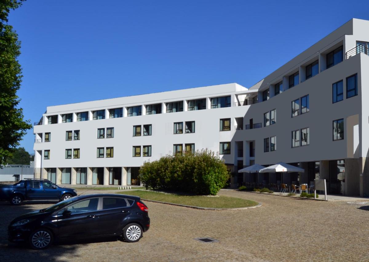 um carro estacionado em um estacionamento em frente a um prédio em Hotel Bienestar Termas de Moncao em Monção
