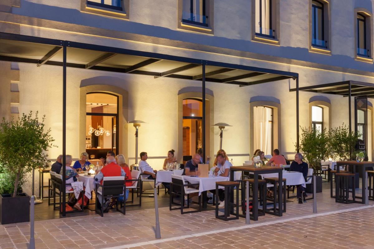 un groupe de personnes assises à des tables sur un patio dans l'établissement Hotel Centre Nautique, à Bonifacio