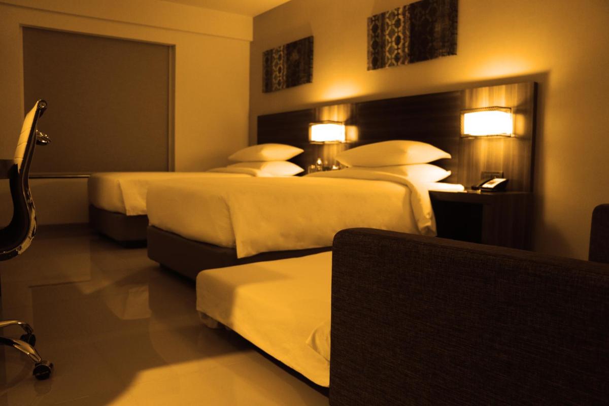a hotel room with two beds and two tables at The Residency Towers, Rameswaram in Rāmeswaram
