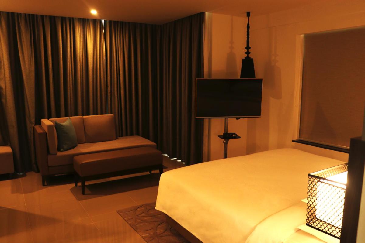 a hotel room with a bed and a chair and a television at The Residency Towers, Rameswaram in Rāmeswaram