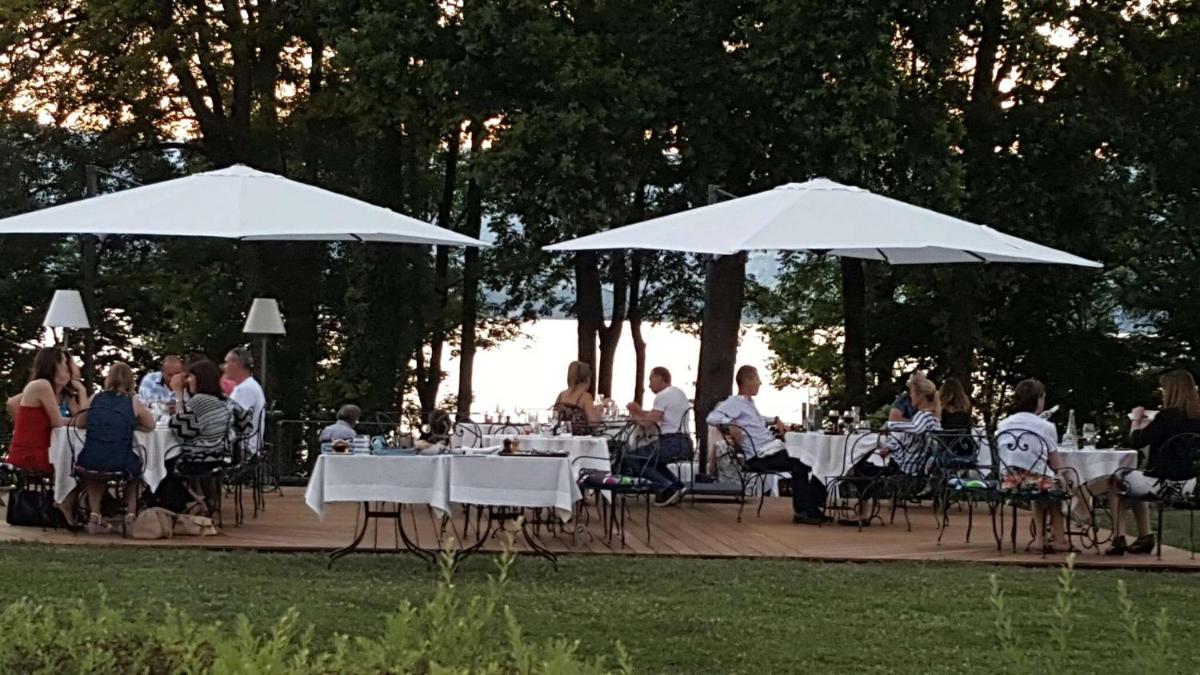 Un groupe de personnes assises à des tables sous des parapluies blancs dans l'établissement Villa Cécile, à Yvoire 98 autres photos