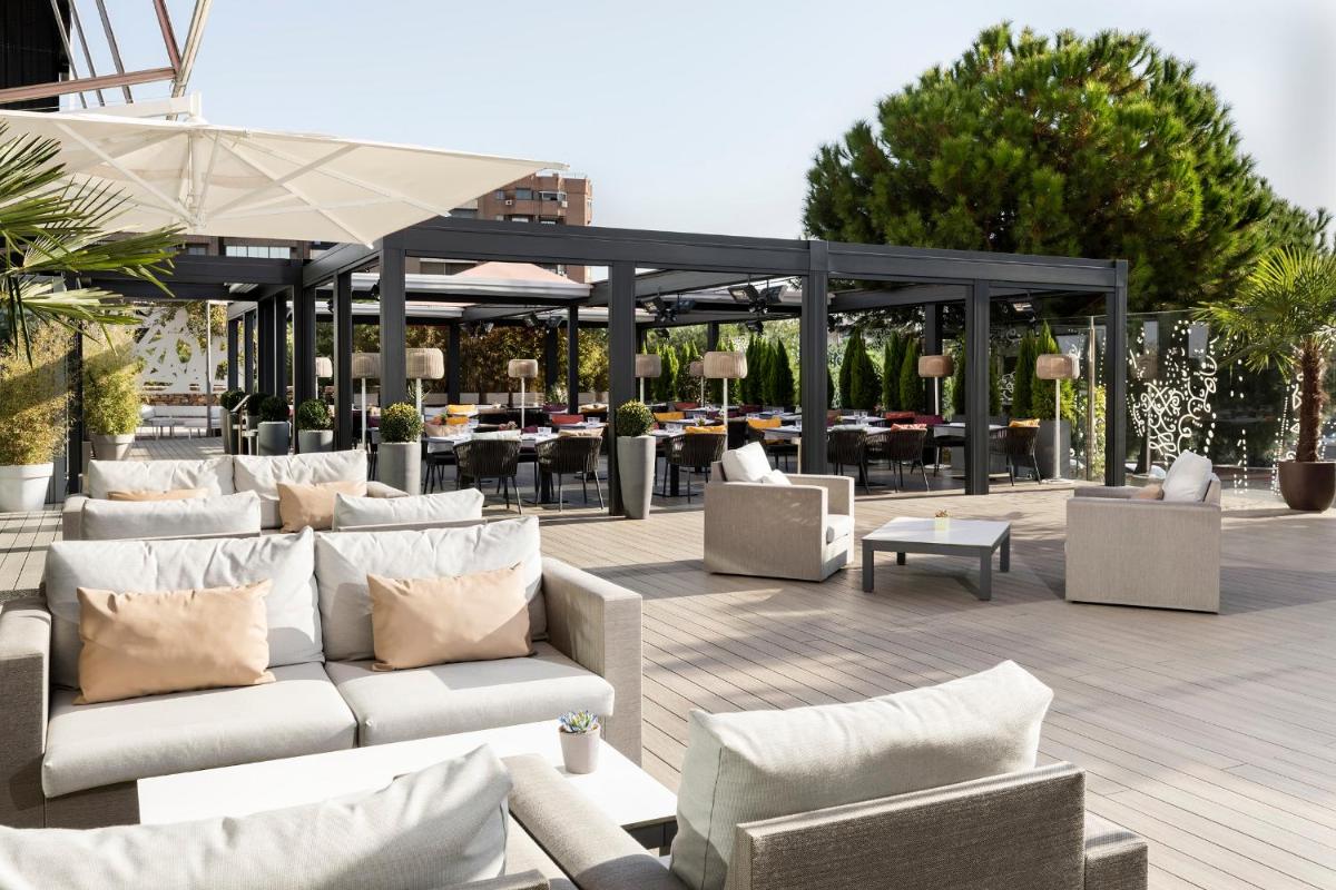 un patio al aire libre con sofás, mesas y sillas en Hotel Puerta America, en Madrid