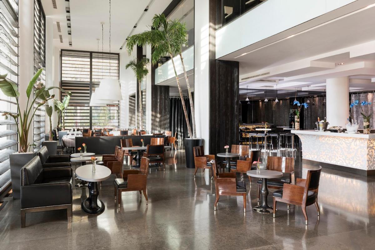Un restaurante con mesas y sillas y un bar. en Hotel Puerta America, en Madrid