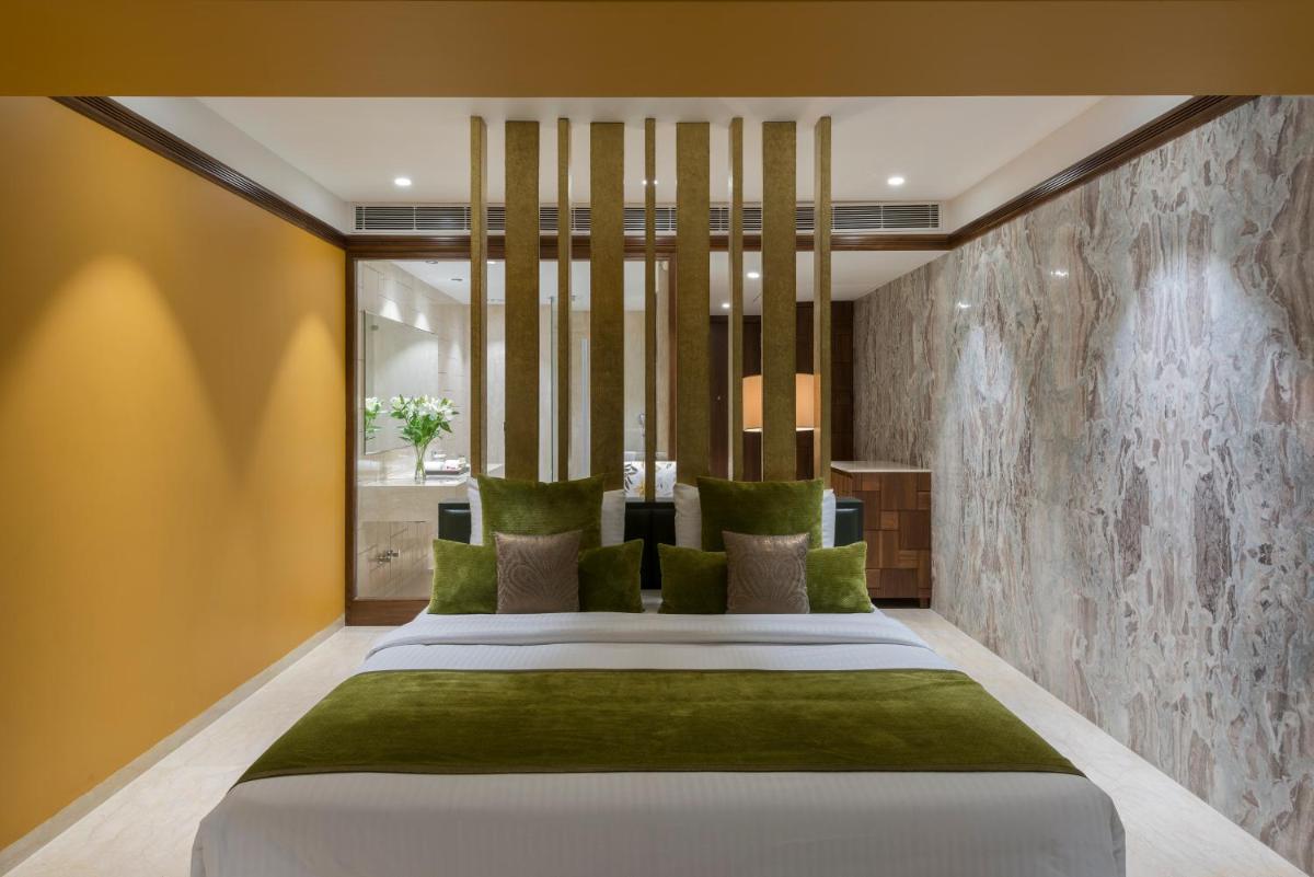 a bedroom with a large white bed with green pillows at Hotel Lakend in Udaipur