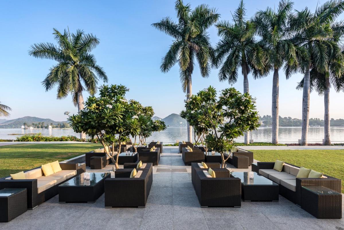 a row of couches with palm trees in the background at Hotel Lakend in Udaipur