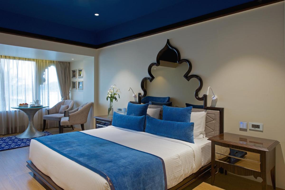 a bedroom with a large bed with blue pillows at Hotel Lakend in Udaipur