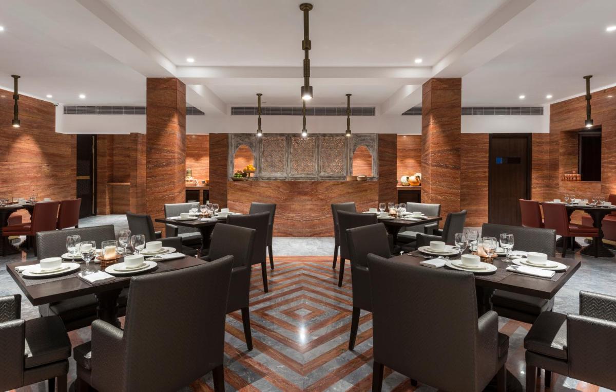 a restaurant with tables and chairs in a room at Hotel Lakend in Udaipur