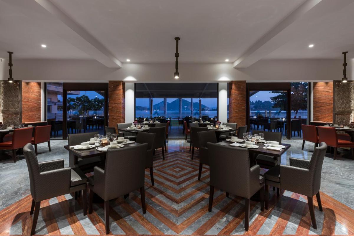 a restaurant with tables and chairs and large windows at Hotel Lakend in Udaipur