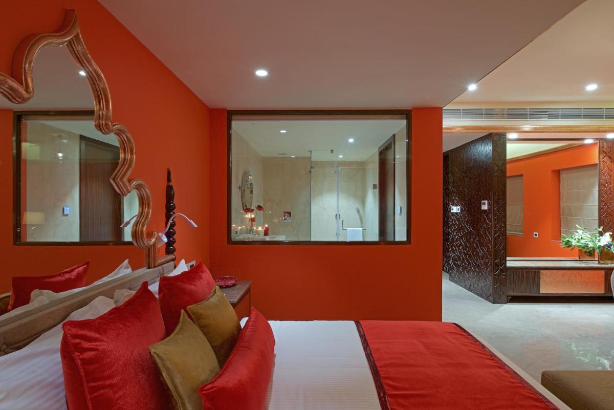 a bedroom with orange walls and a bed with red pillows at Hotel Lakend in Udaipur