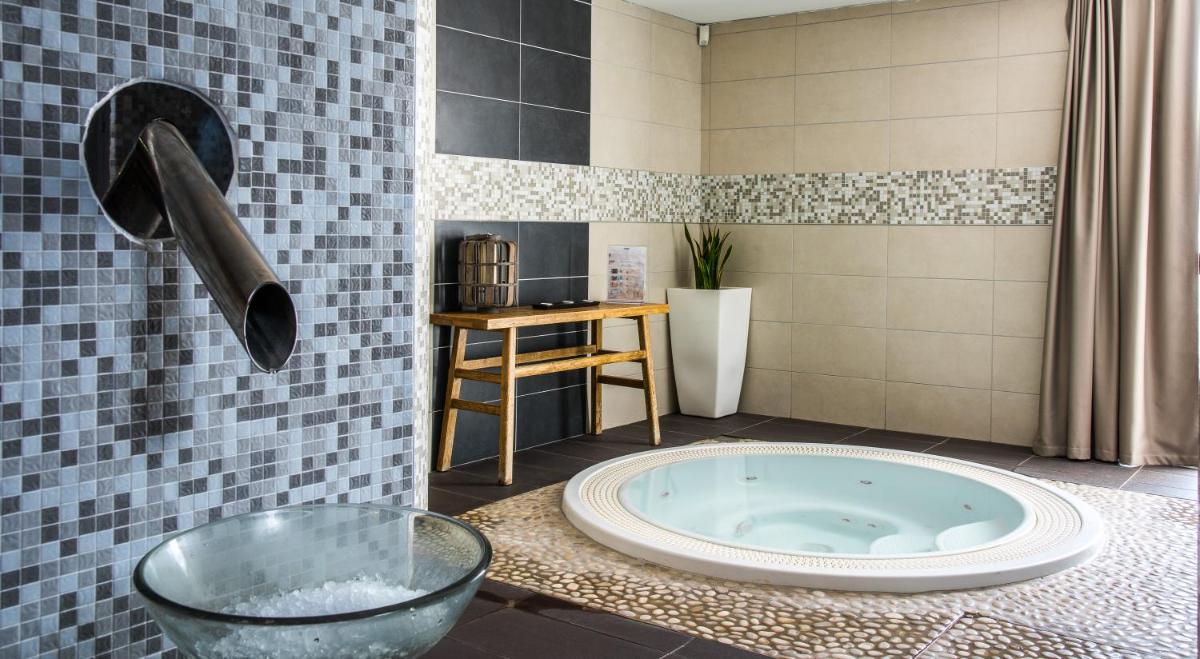 - une salle de bains avec une grande baignoire au milieu d'une pièce dans l'établissement Domaine la Charpinière, The Originals Collection, à Saint-Galmier