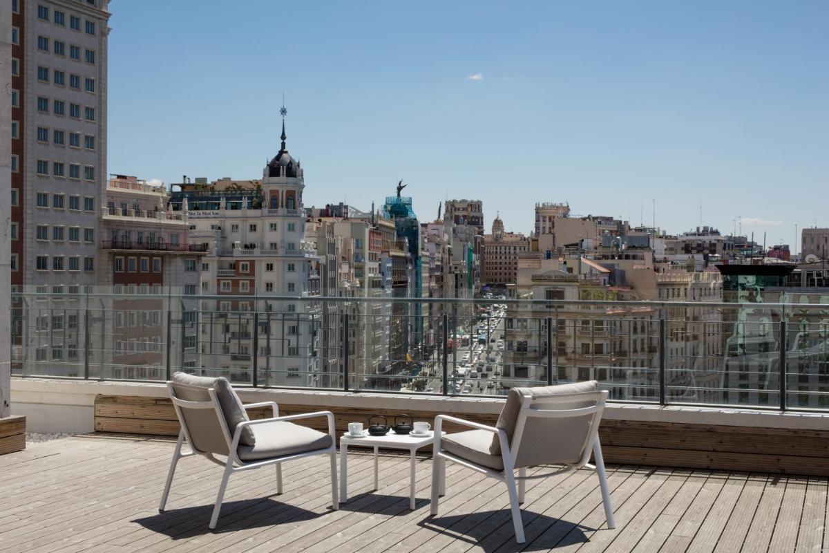 Un balcón con 2 sillas, una mesa y una ciudad en Barceló Torre de Madrid, en Madrid