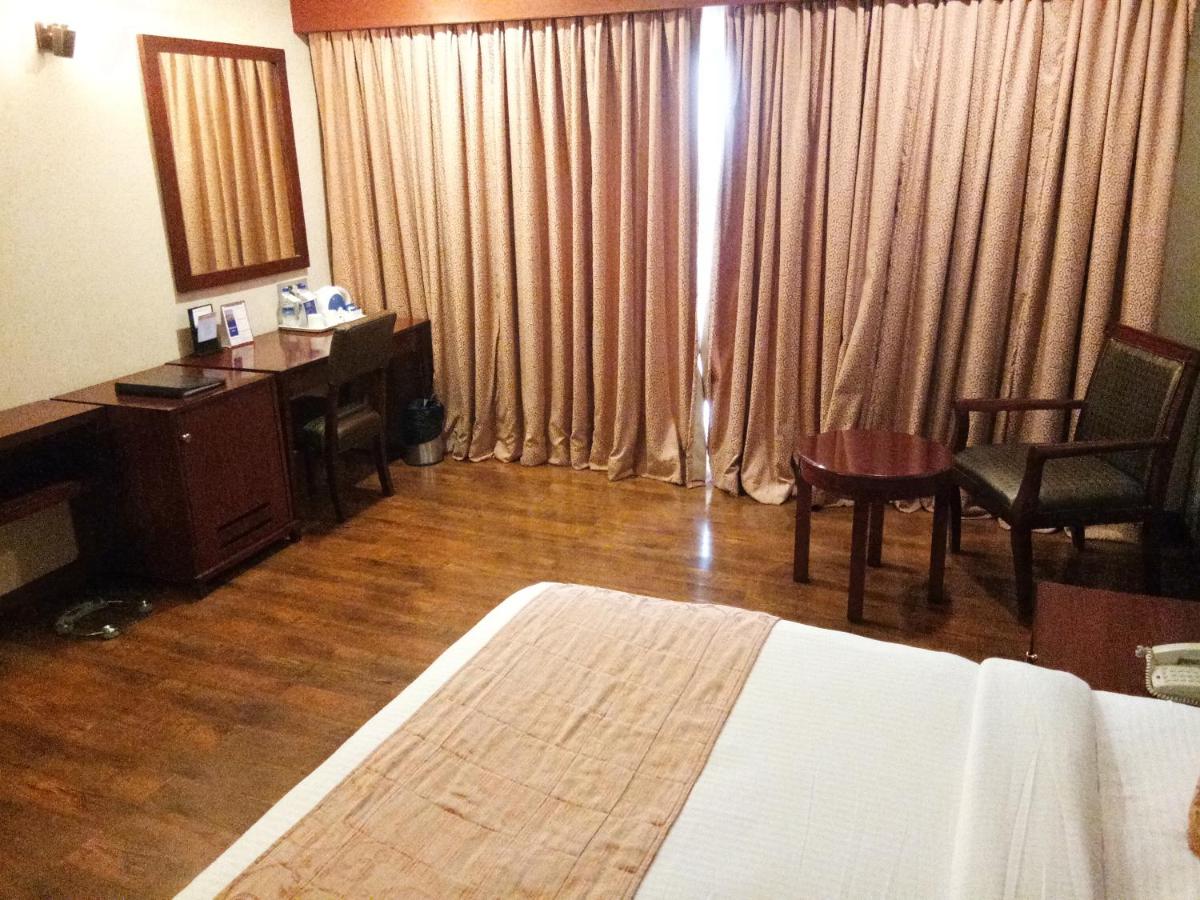 a hotel room with a bed and a desk and a mirror at Fortune Select Grand Ridge, Tirupati - Member ITC Hotels' Group in Tirupati