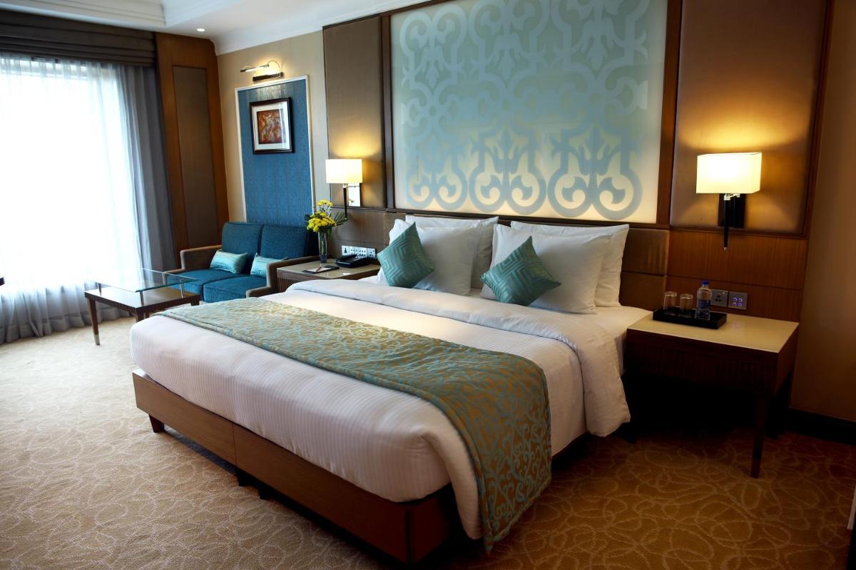 a hotel room with a large bed and a chair at Ramada Plaza Chennai in Chennai