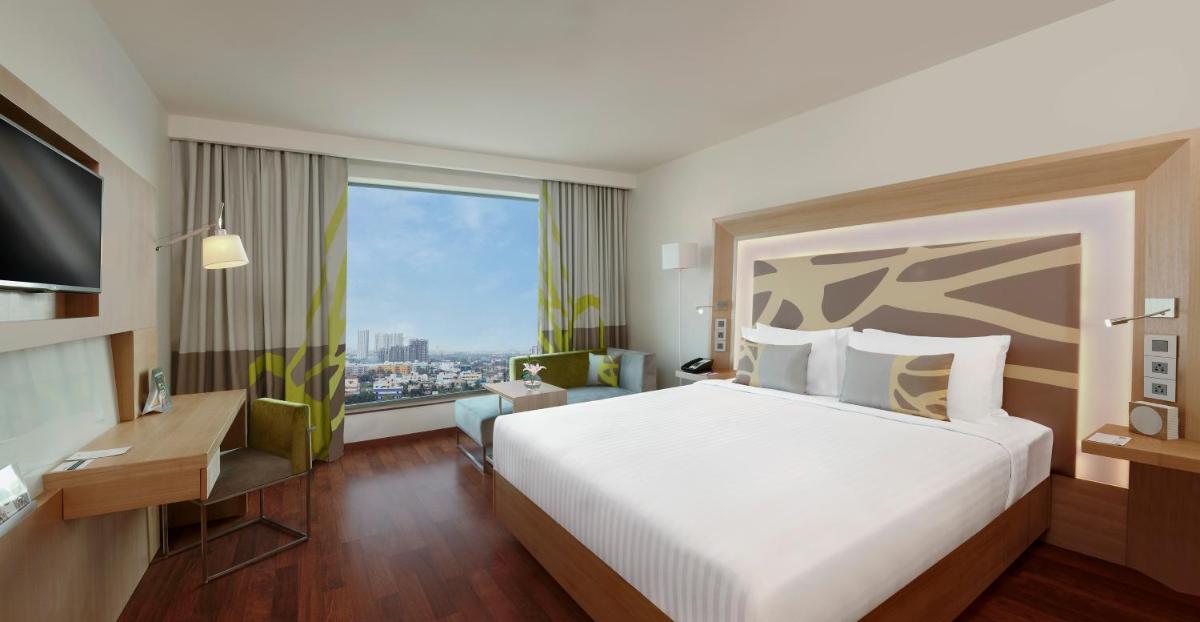 a hotel room with a large bed and a large window at Novotel Chennai OMR in Chennai