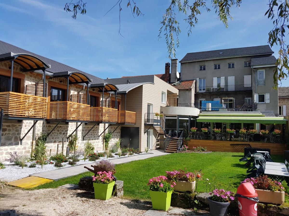 un bâtiment avec une cour ornée de plantes et de fleurs dans l'établissement Logis SPA Hotel Restaurant De La Poste, à Tence