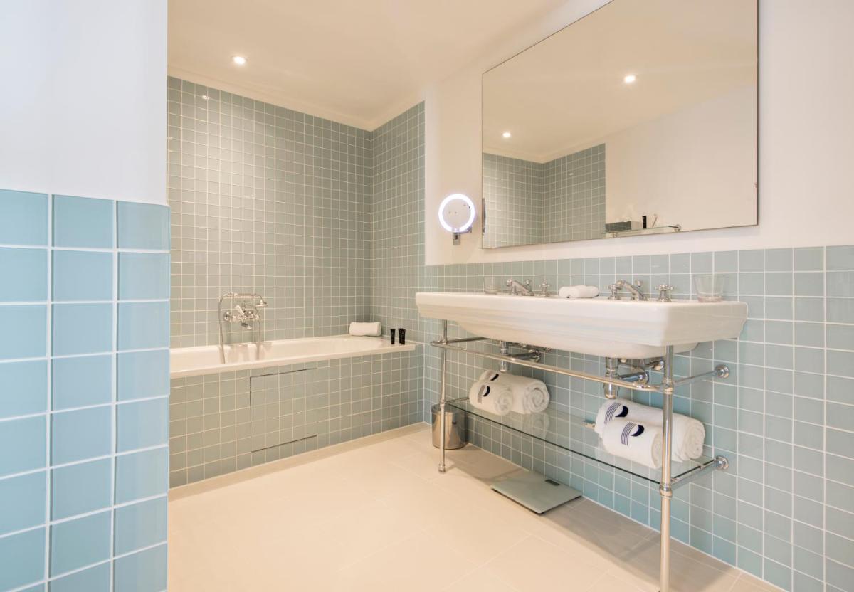une salle de bain avec un lavabo, un miroir et une baignoire dans l'établissement Hotel Parister Piscine & Spa, à Paris