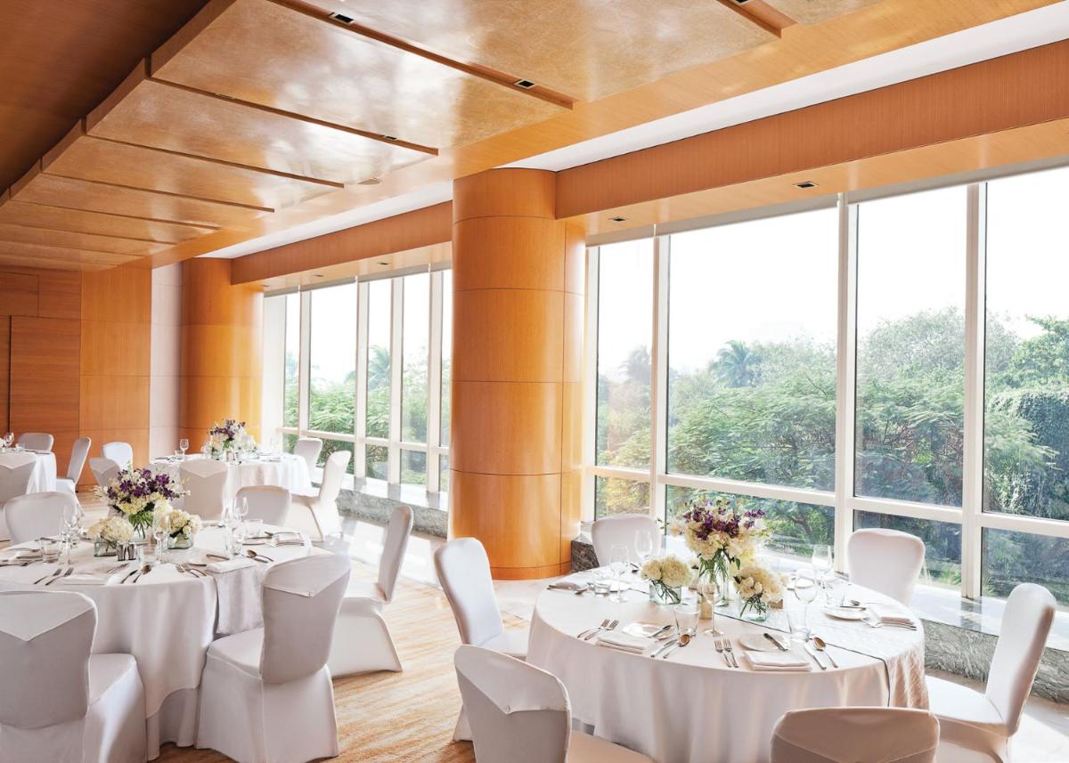 a room with white tables and white chairs and windows at Four Seasons Hotel Mumbai in Mumbai
