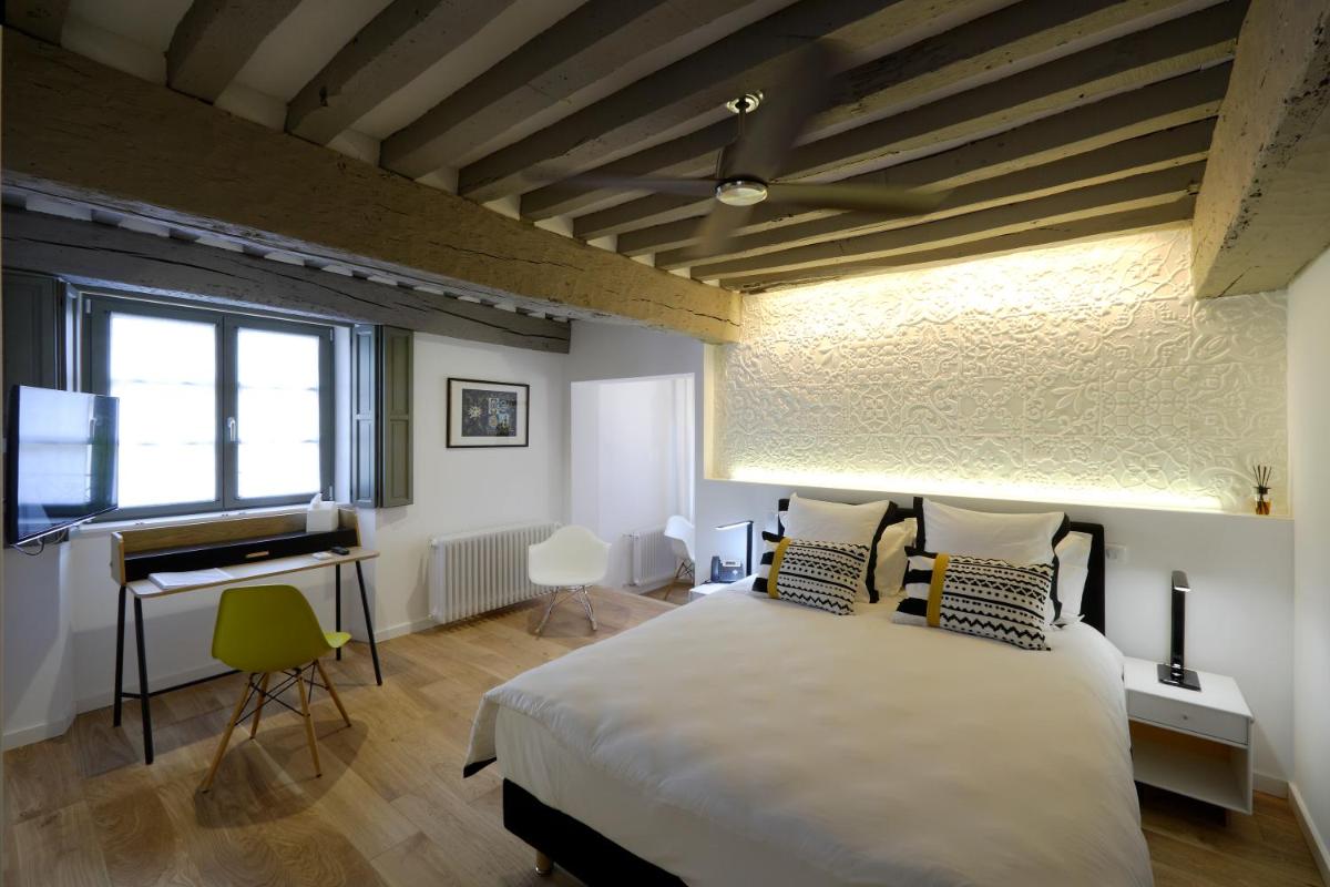 une chambre avec un grand lit et un piano dans l'établissement Les Maisons du Pont - Charme & Caractère, à Aubusson