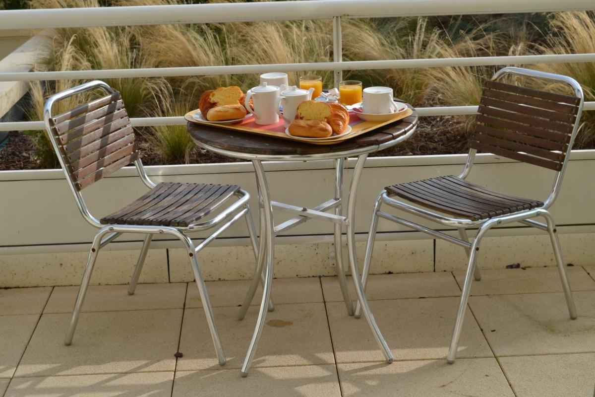 une table avec deux chaises et un plateau de nourriture dans l'établissement Almoria Hôtel & SPA, à Deauville