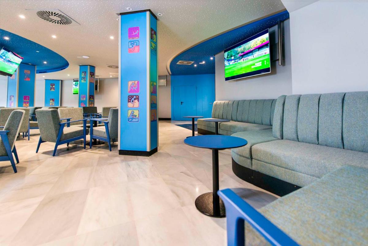 Una sala de espera con un sofá y un televisor. en Spring Hotel Vulcano, en Playa de las Américas