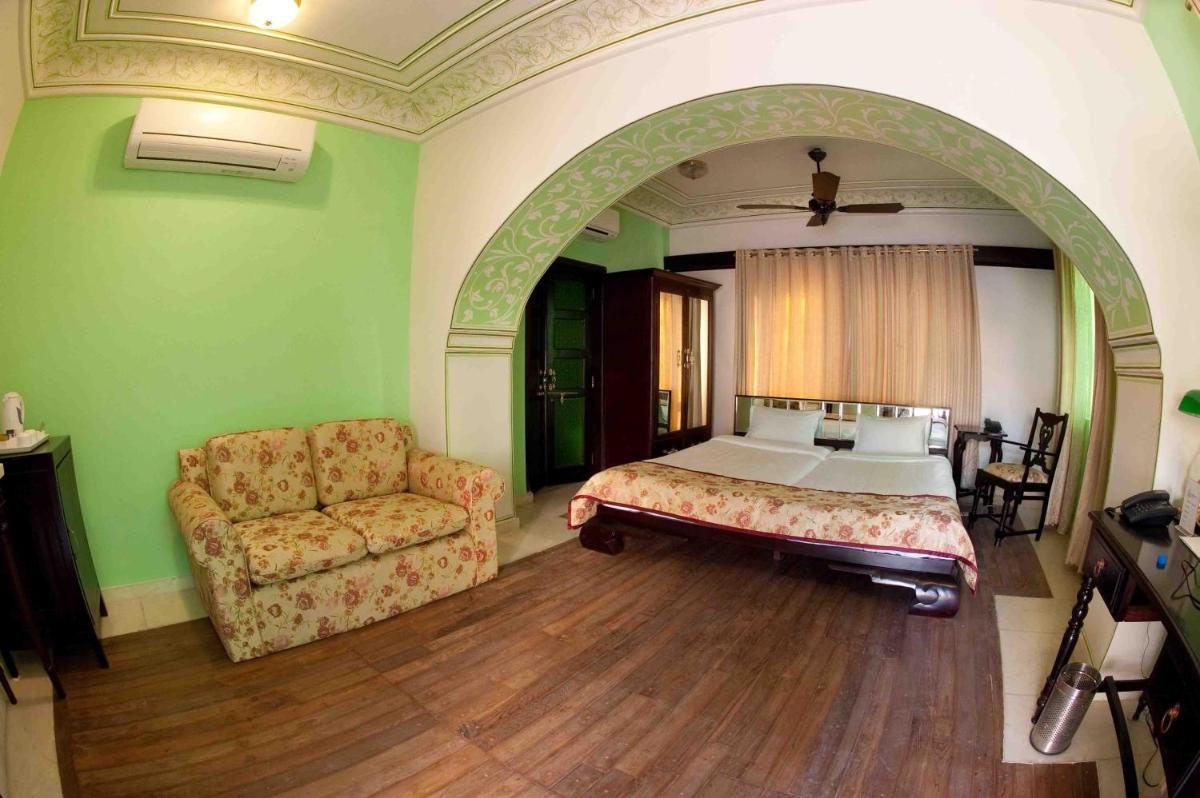 a bedroom with a bed and a couch and a chair at Royal Heritage Haveli - By Leisure Hotels in Jaipur