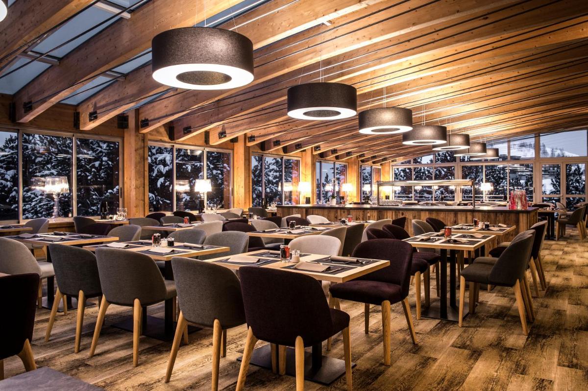 un restaurant avec des plafonds en bois, des tables et des chaises dans l'établissement Le Pic Blanc, à L'Alpe-d'Huez 31 autres photos