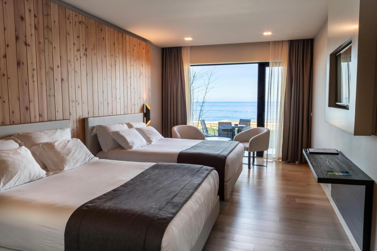 duas camas em um quarto de hotel com vista para o oceano em Pedras do Mar Resort & Spa em Fenais da Luz