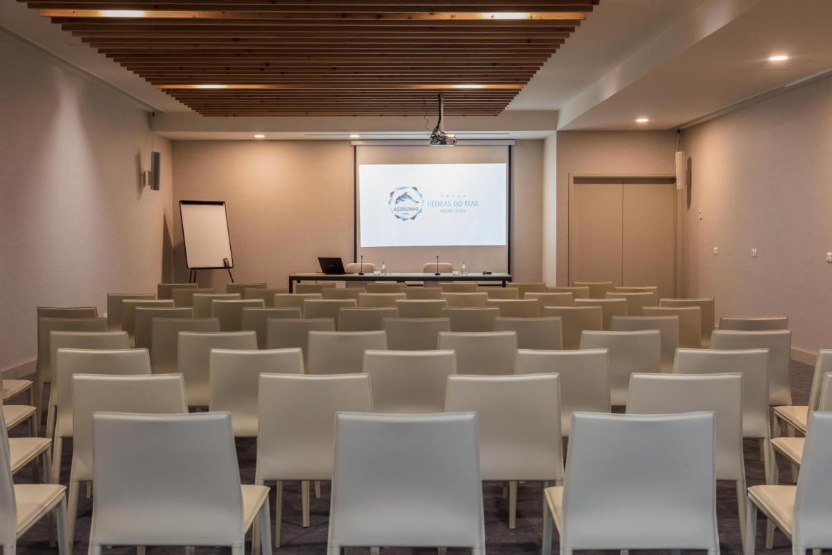 uma sala de conferências com cadeiras e um ecrã de projecção em Pedras do Mar Resort & Spa em Fenais da Luz