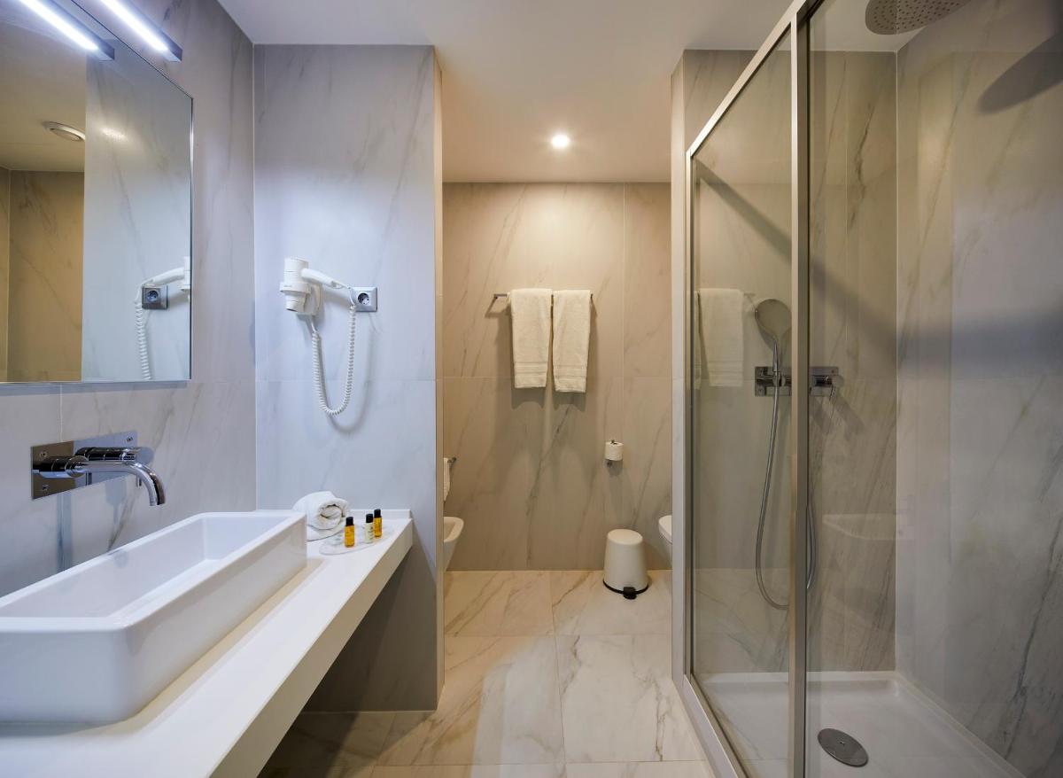 um banheiro com pia e chuveiro em Alcazar Hotel & SPA em Monte Gordo