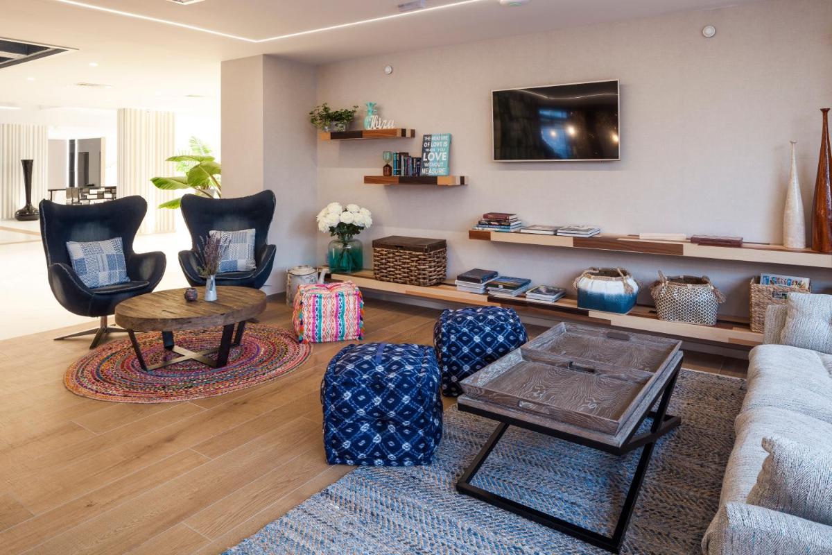 Una sala de estar con un sofá y sillas y un televisor. en Ibiza Corso Hotel & Spa, en Ibiza